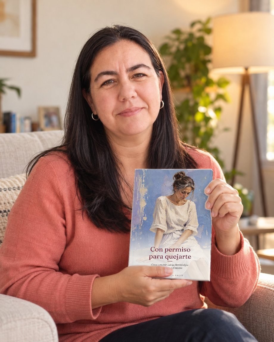 Doc Adriana Angel sentada en su sillón, sosteniendo su libro Con permiso para quejarte
